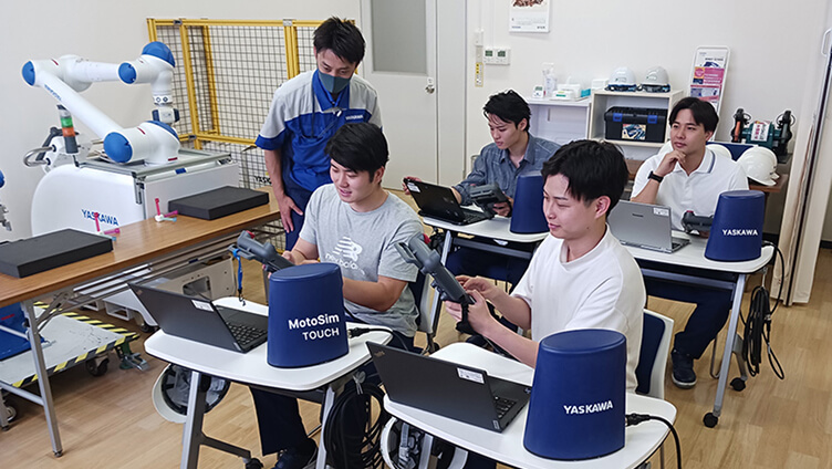 教室内でロボット操作の講義を受ける学生たち